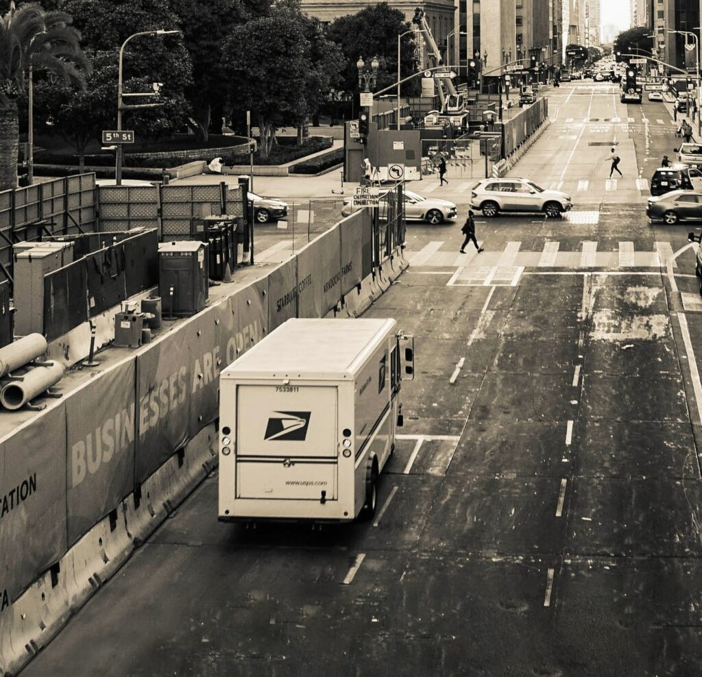 A photo of a mail truck driving down a city street