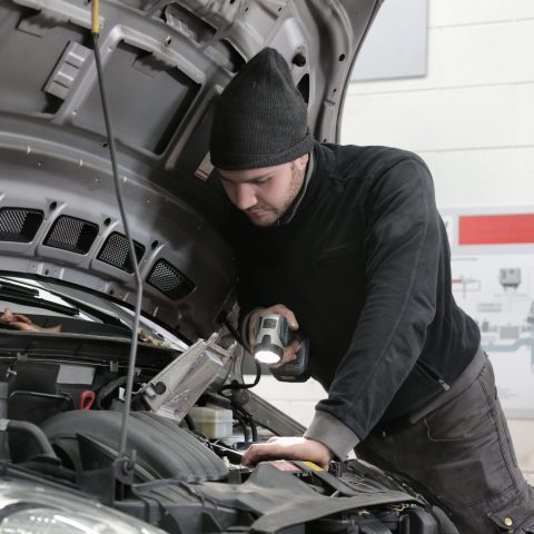 Service technician working under the hood of a vehicle